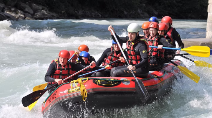 Group of rafters paddling through powerful white water rapids on the Nile River in Jinja, Uganda, surrounded by lush green scenery.
