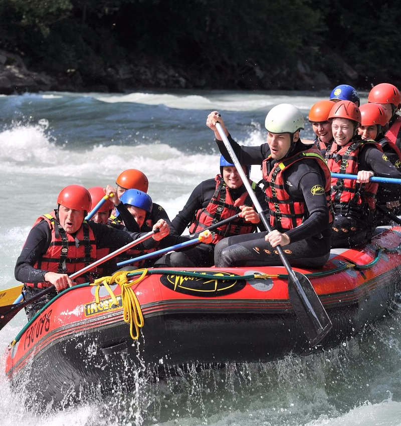 Group of rafters paddling through powerful white water rapids on the Nile River in Jinja, Uganda, surrounded by lush green scenery.
